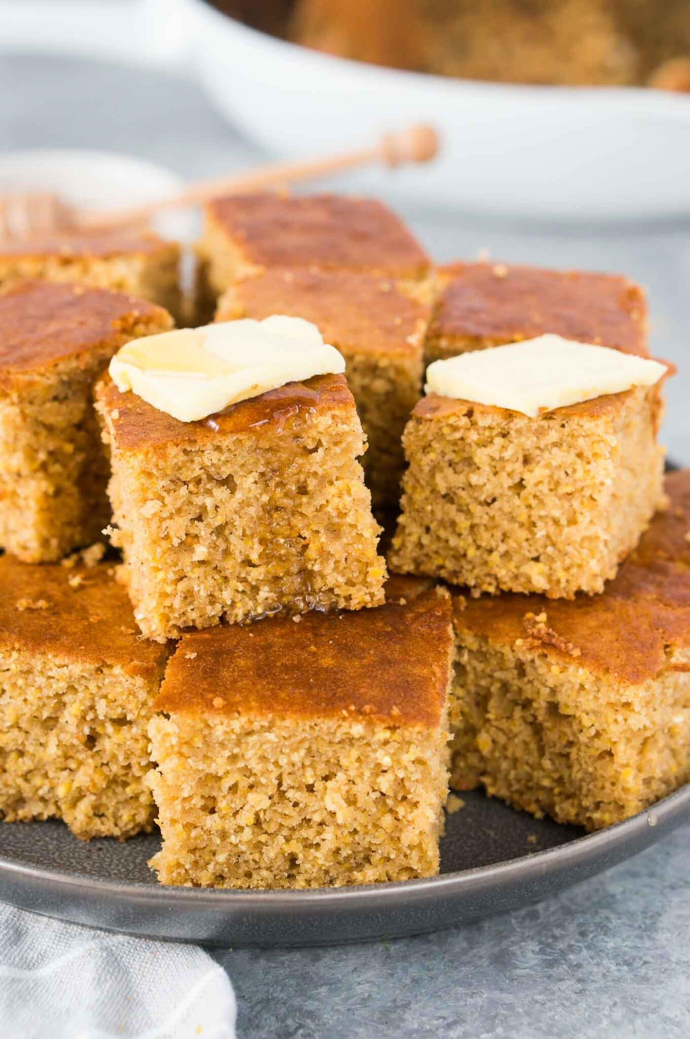 cornbread squares with butter & honey on a plate