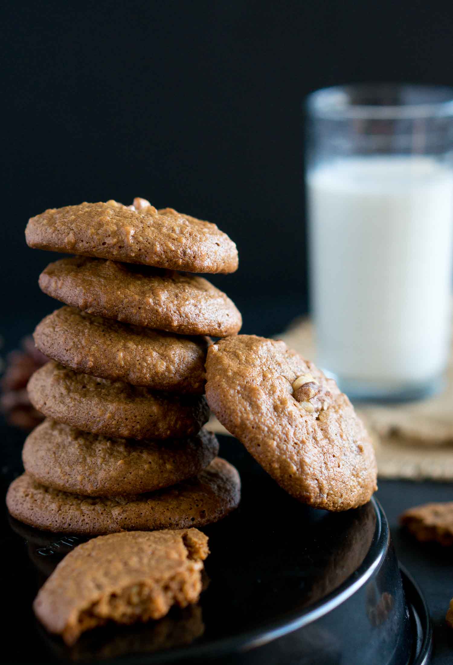 A close up of walnut cookies and milk in the background