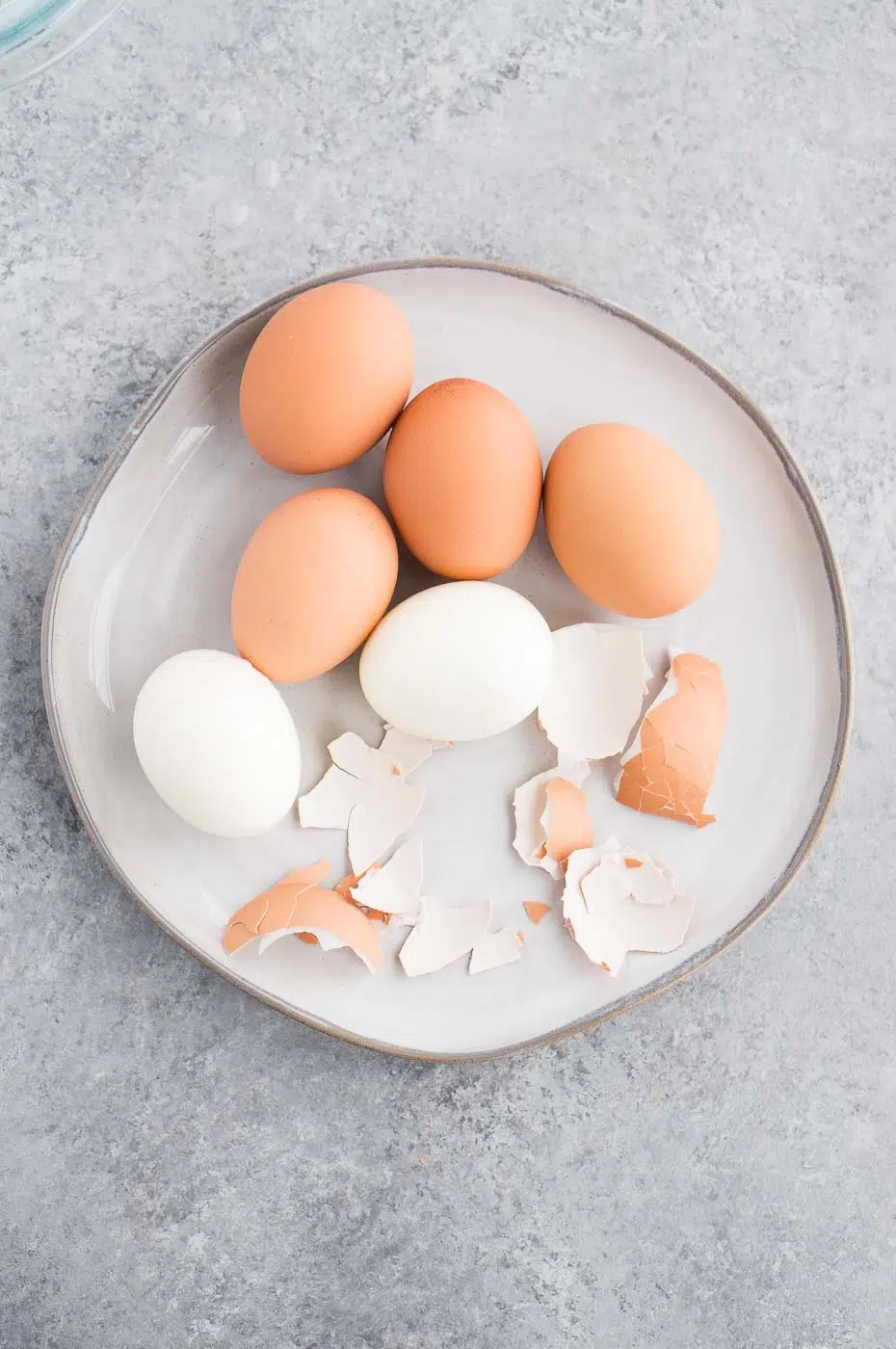 peeled and unpeeled eggs on a plate