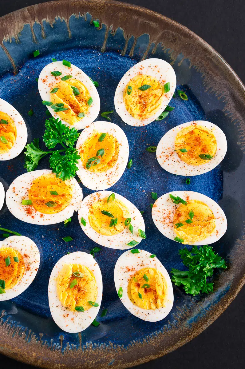 easy to peel hard boiled eggs cut in half on a blue platter