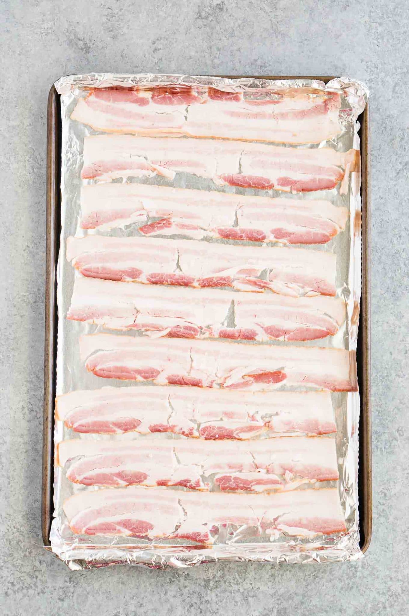 raw bacon on baking sheet