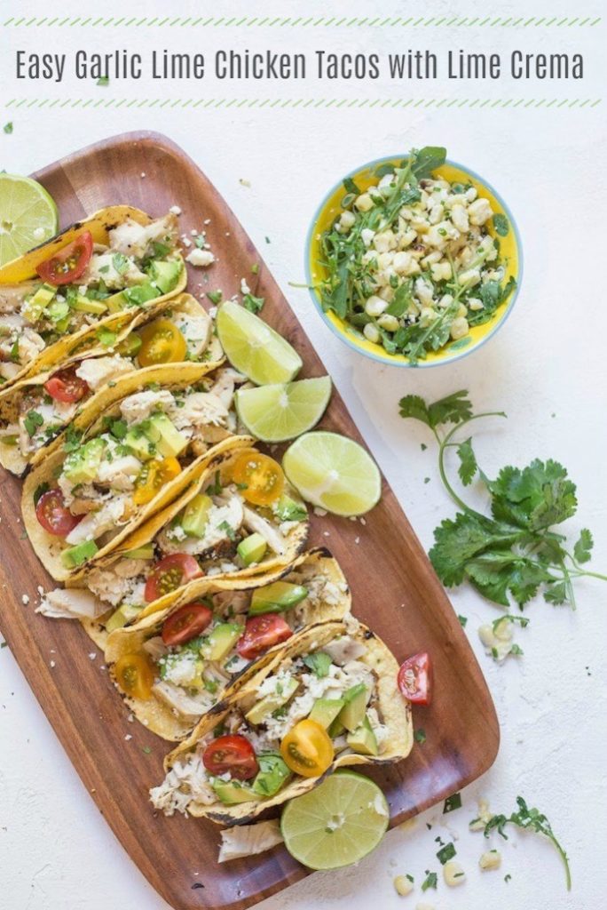 chicken tacos with avocado and tomatoes on a wooden platter
