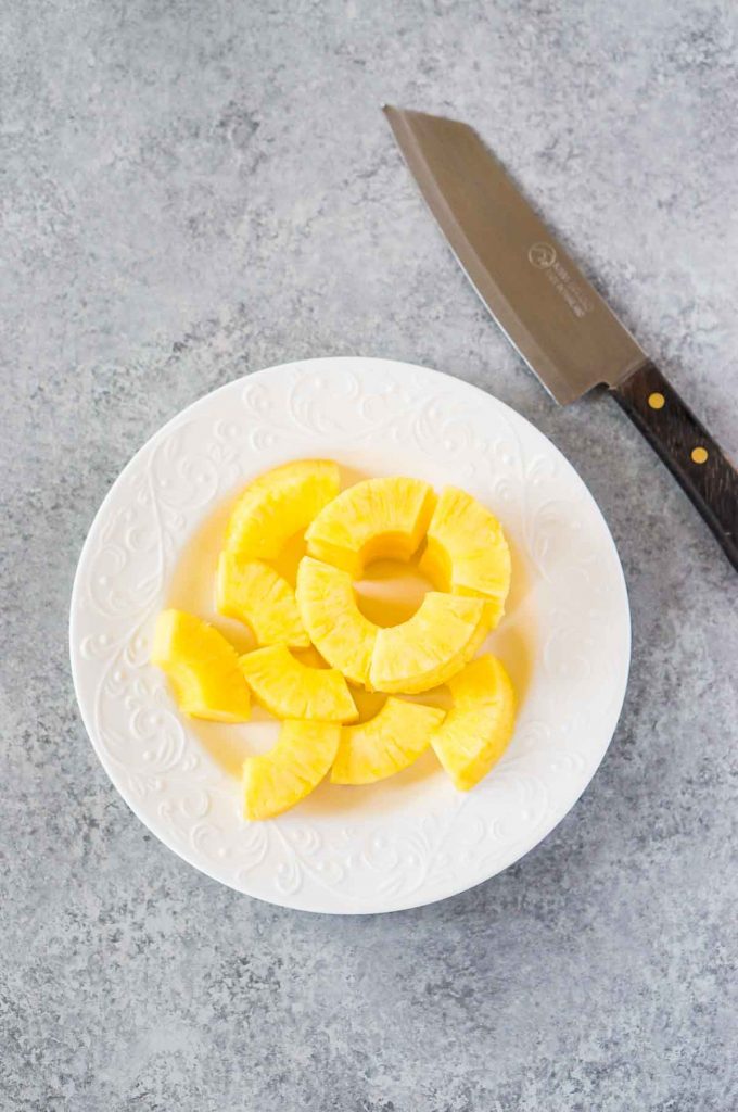 cut pineapple on a plate for making bacon wrapped pineapple bites