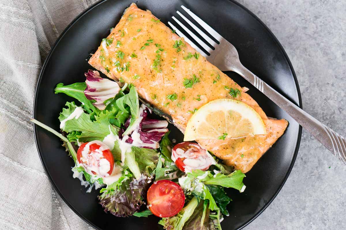 baked salmon on a plate with a green salad