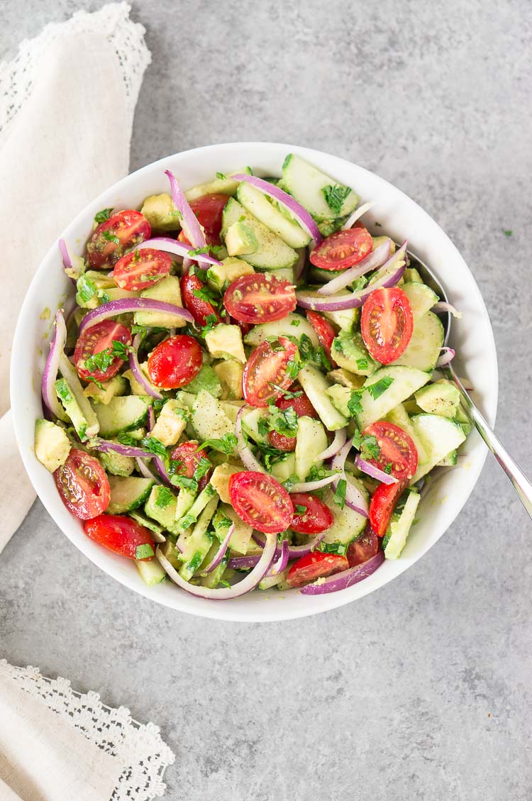 tomato cucumber and avocado salad in a white bowl