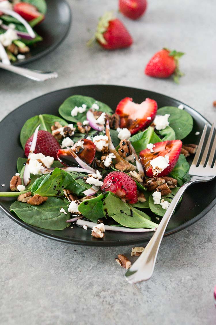 strawberry spinach salad with balsamic dressing and pecans on a plate