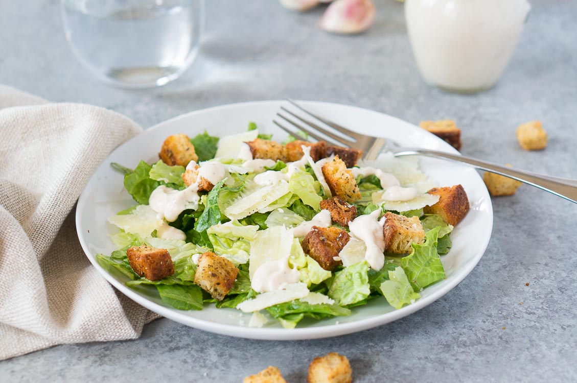 homemade caesar salad recipe with dressing and croutons on a plate with a fork
