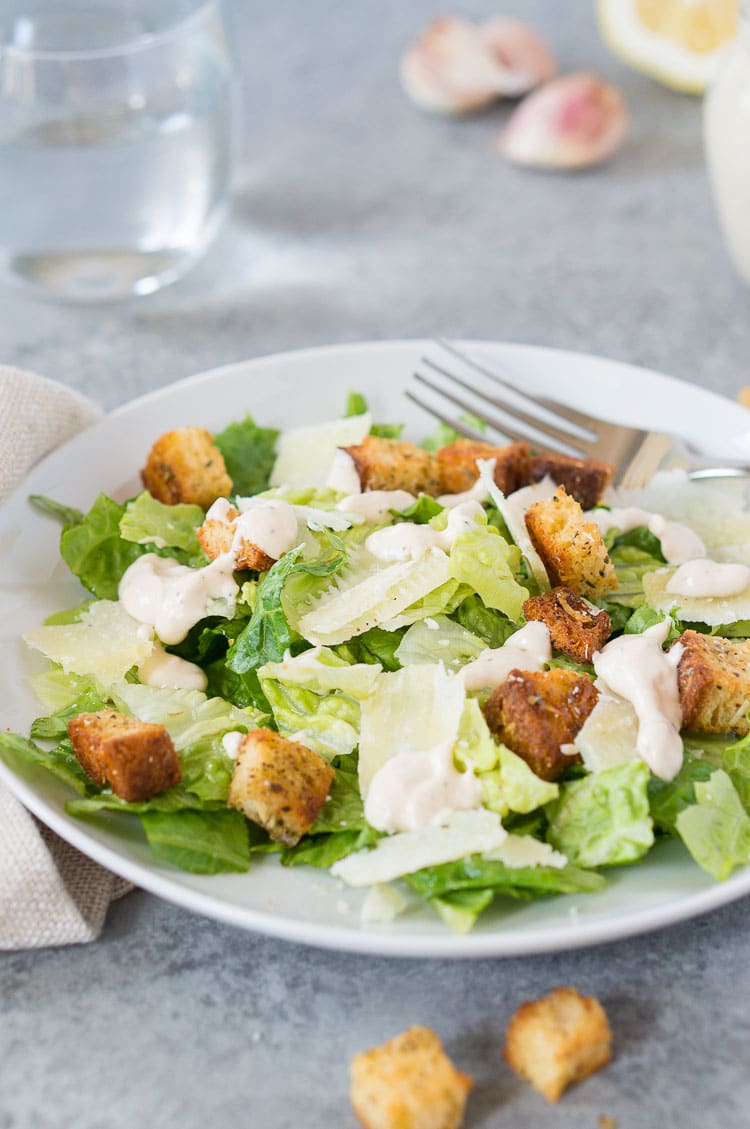 best caesar salad with caesar dressing and homemade croutons on a plate with a fork