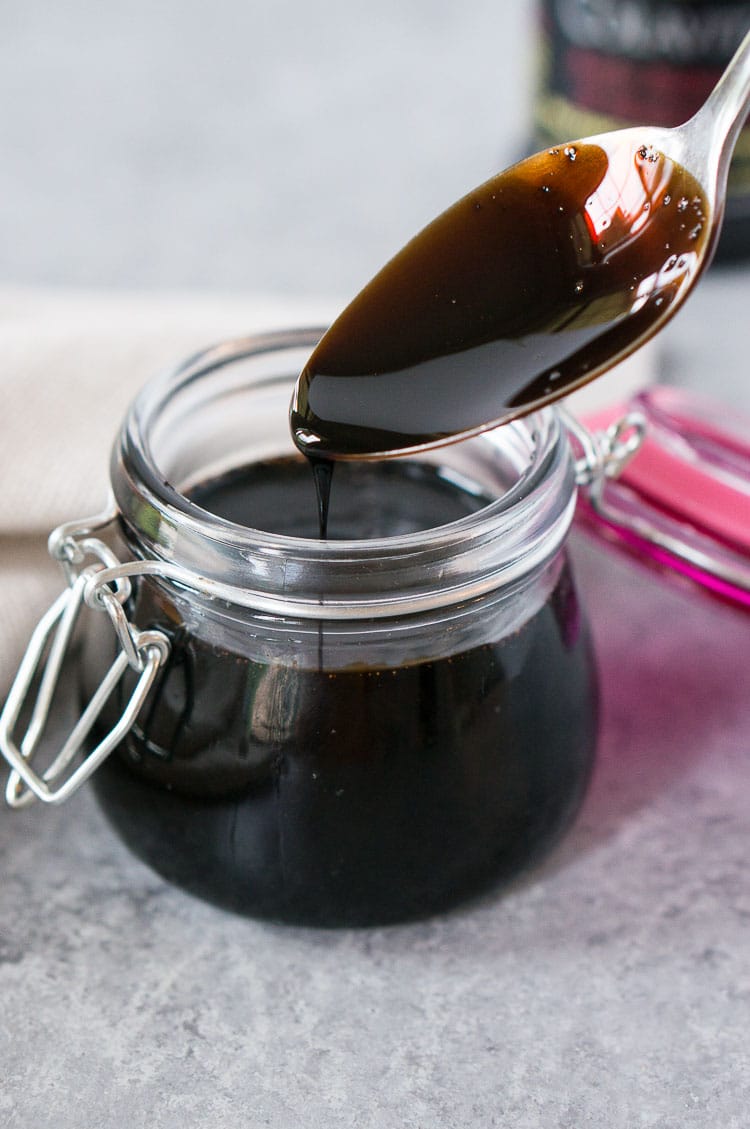 scooping with a spoon some balsamic glaze from a jar