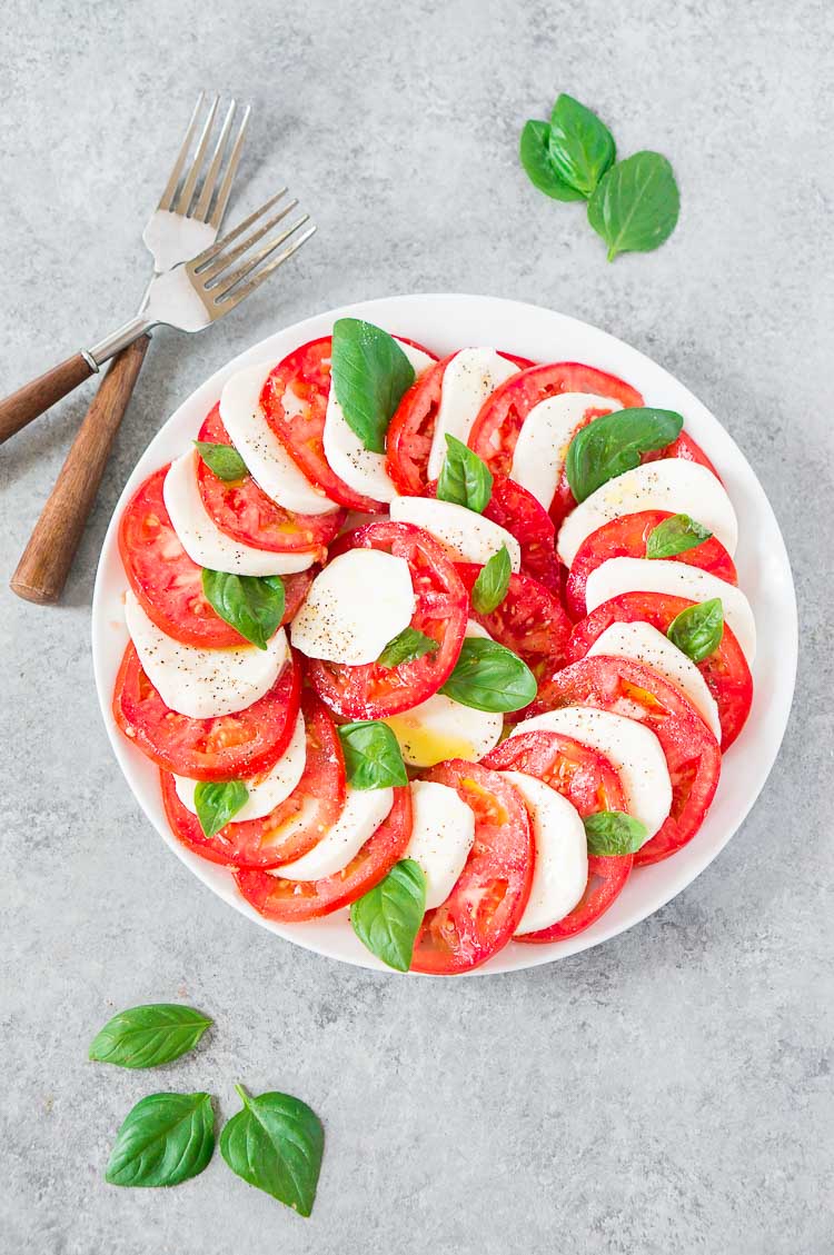 class caprese salad - insalata caprese on a white plate and with forks