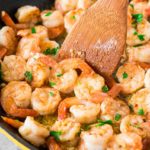 easy shrimp scampi recipe in a skillet with a wooden spoon