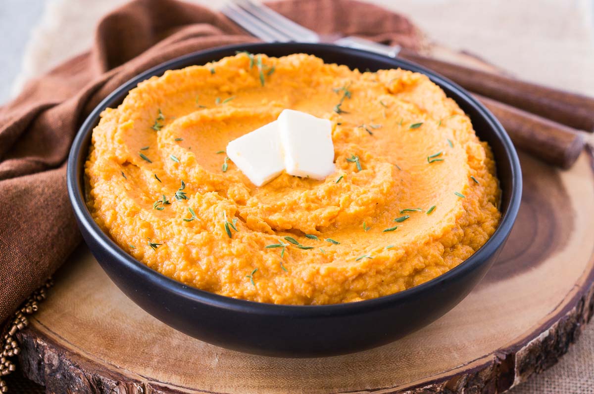 creamy sweet potato mash with thyme in a black bowl