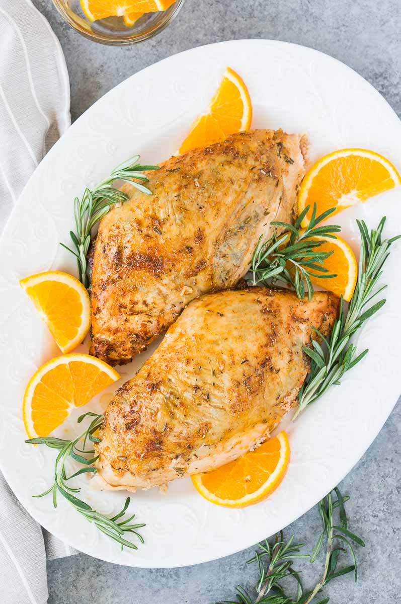 oven roasted turkey breasts on a platter with rosemary and orange slices