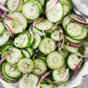 close up of sliced cucumbers and red onion in a bowl