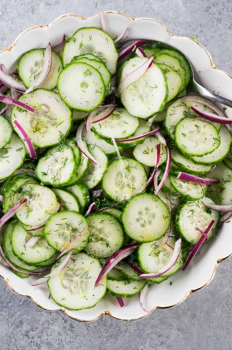 close up of sliced cucumbers and red onion in a bowl