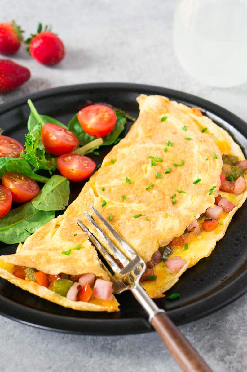 western omelet with greens and cherry tomatoes on a plate