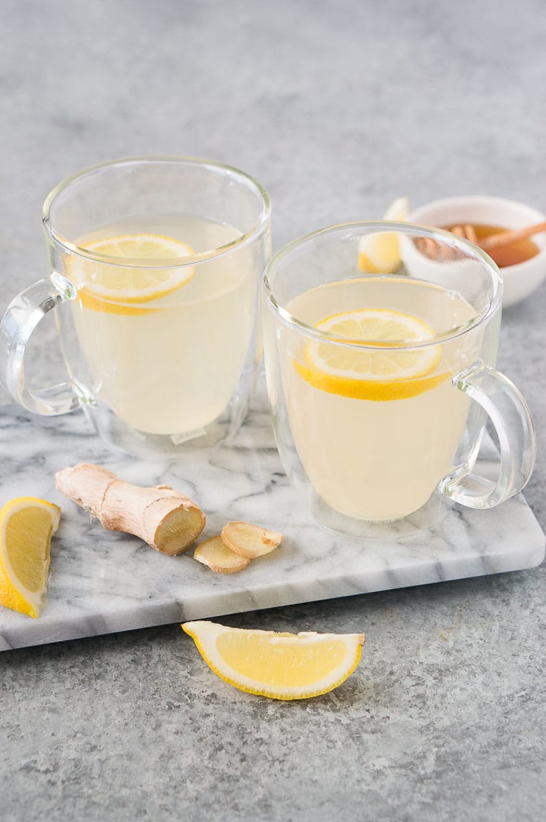 cups with lemon and ginger tea on a board