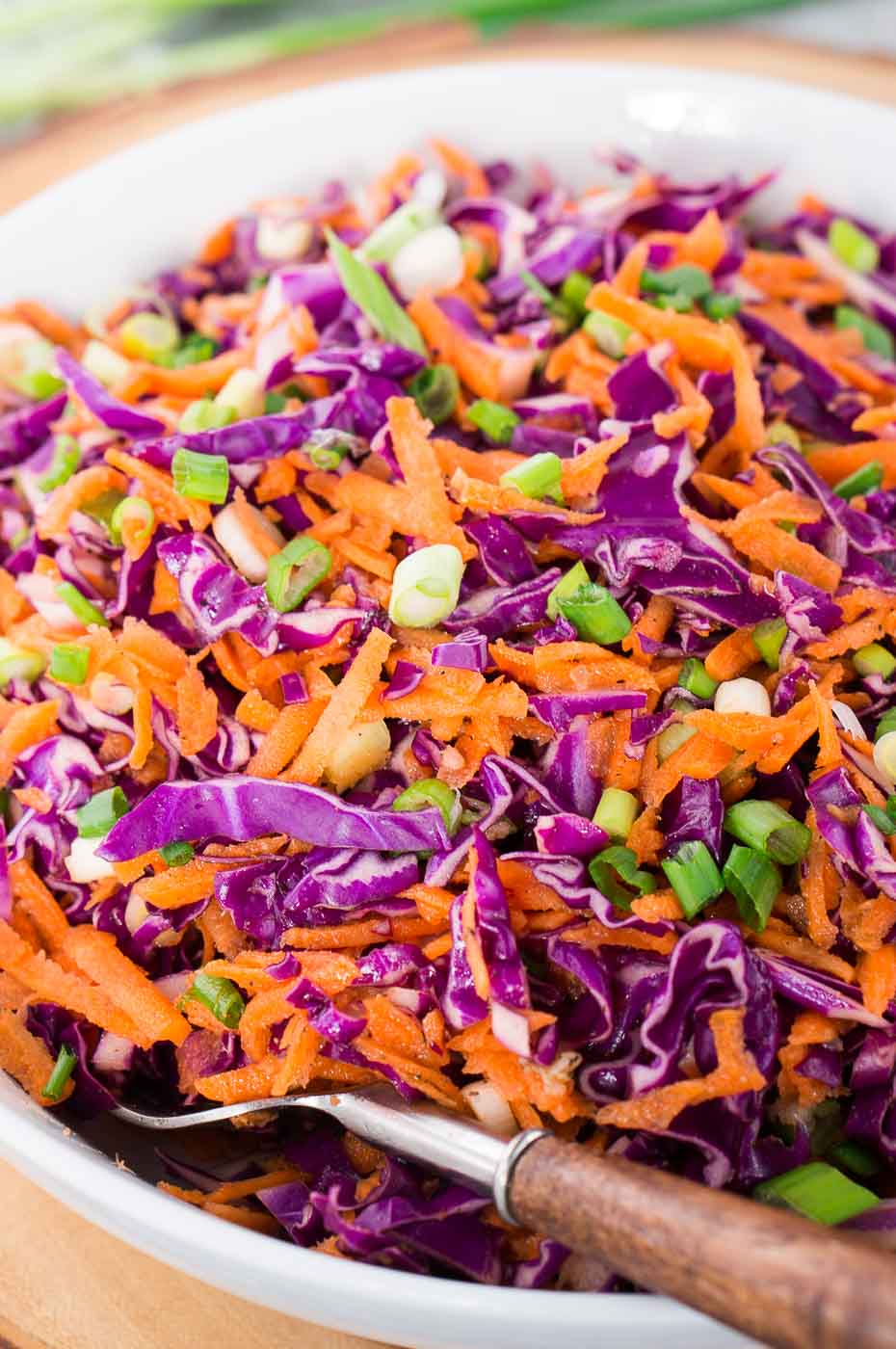 close up of carrots and red cabbage coleslaw in a bowl with a fork