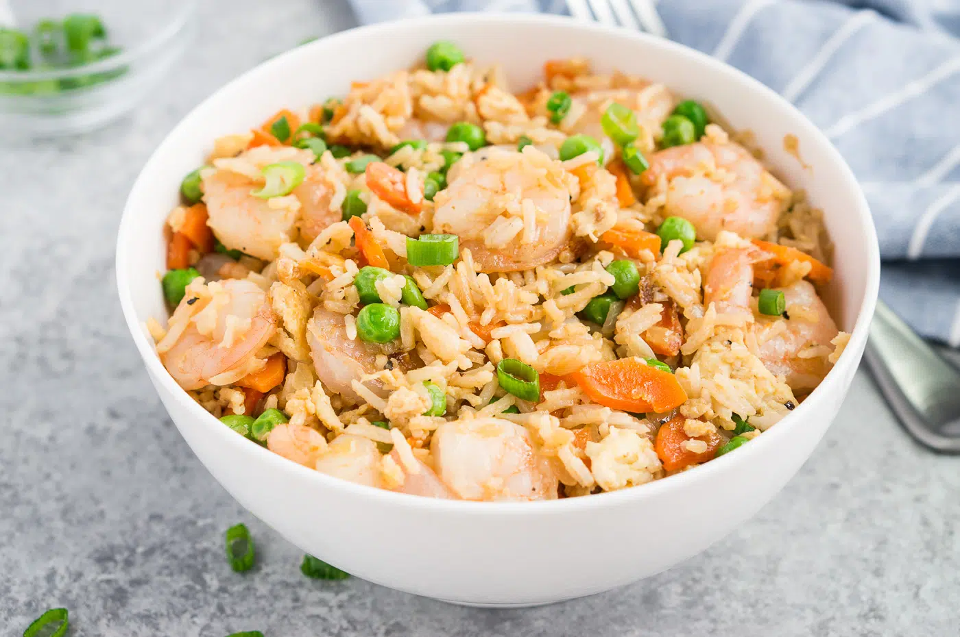 Close-up shot of a bowl of delicious shrimp fried rice with fresh green onions for garnish.