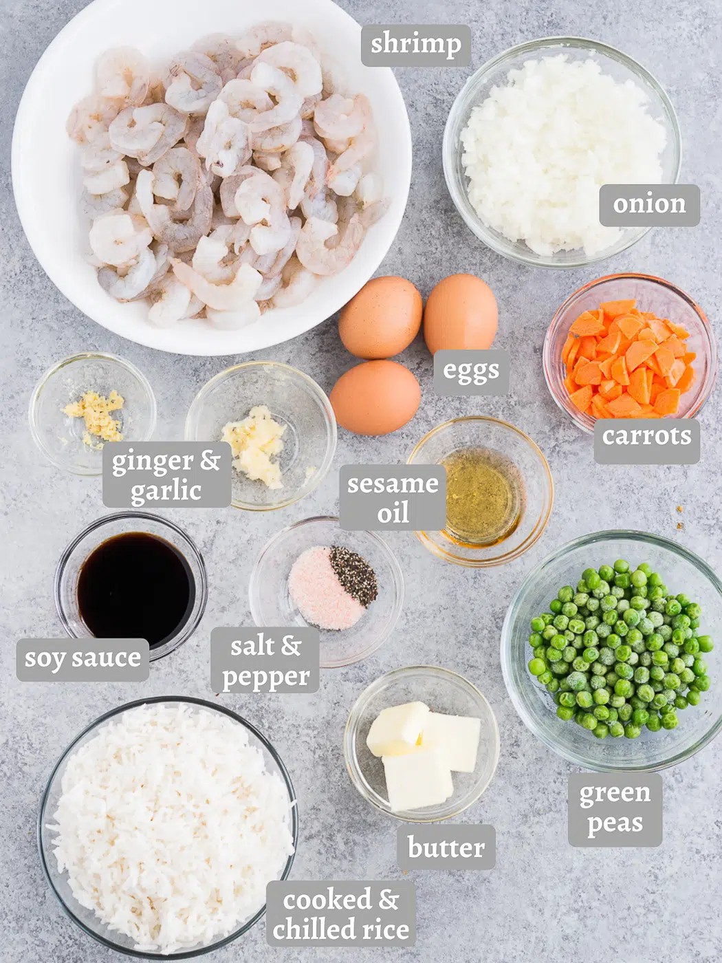 A selection of fresh ingredients laid out for making shrimp fried rice, including shrimp, vegetables, eggs, and seasonings.