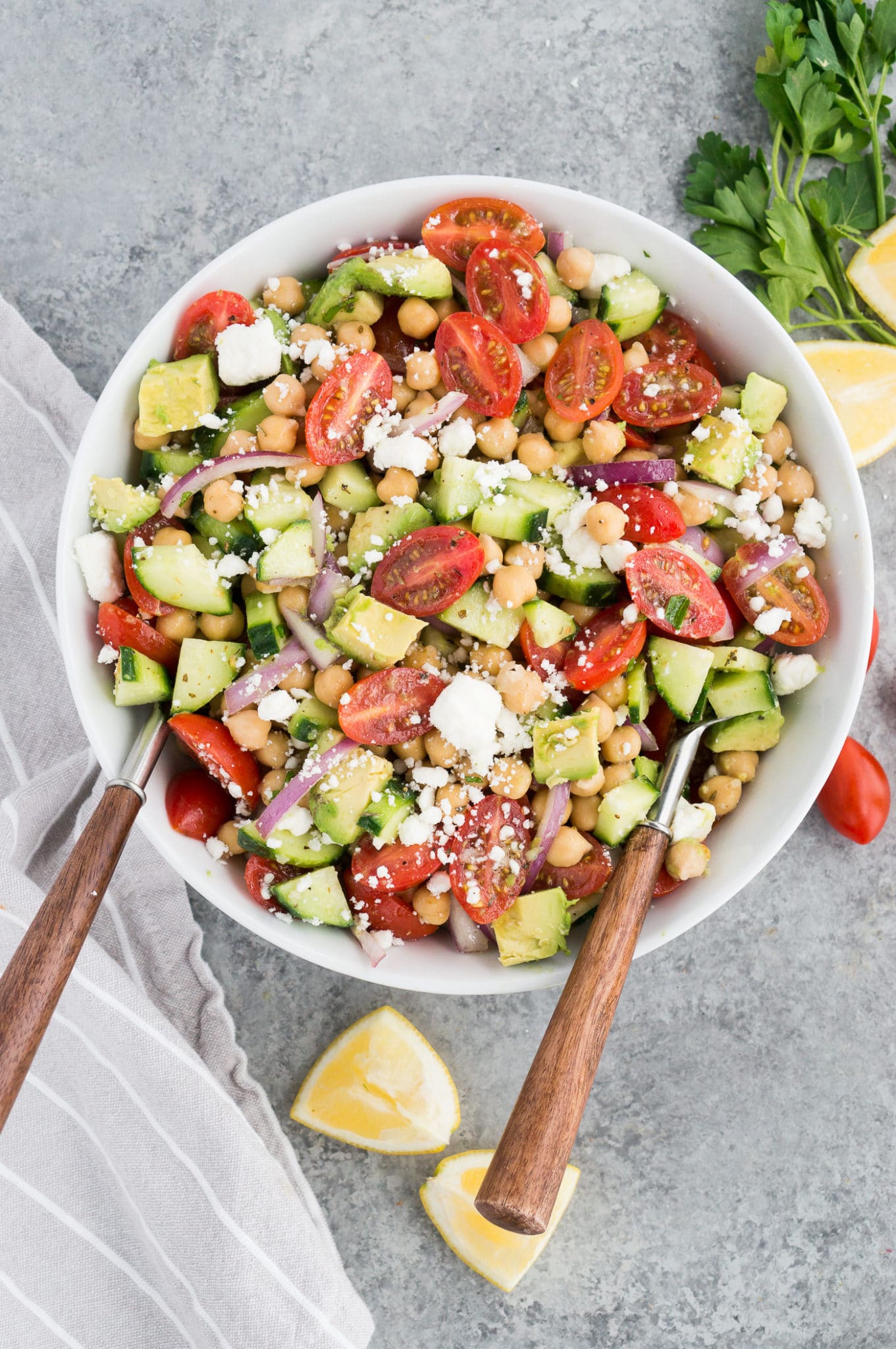 chickpea cucumber salad in a white bowl with salad tongs