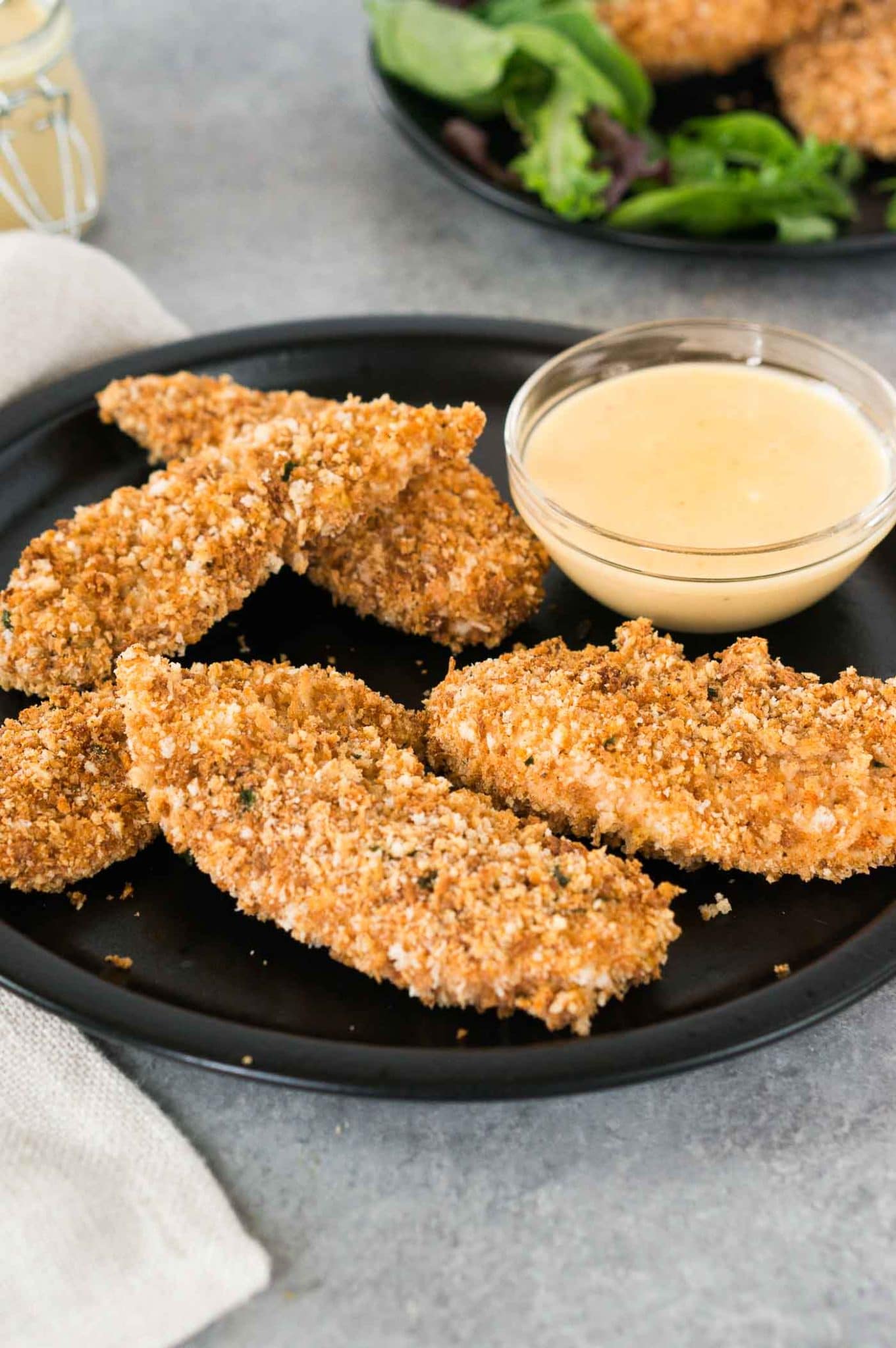 healthy oven baked chicken tenders served with honey mustard sauce on a black plate
