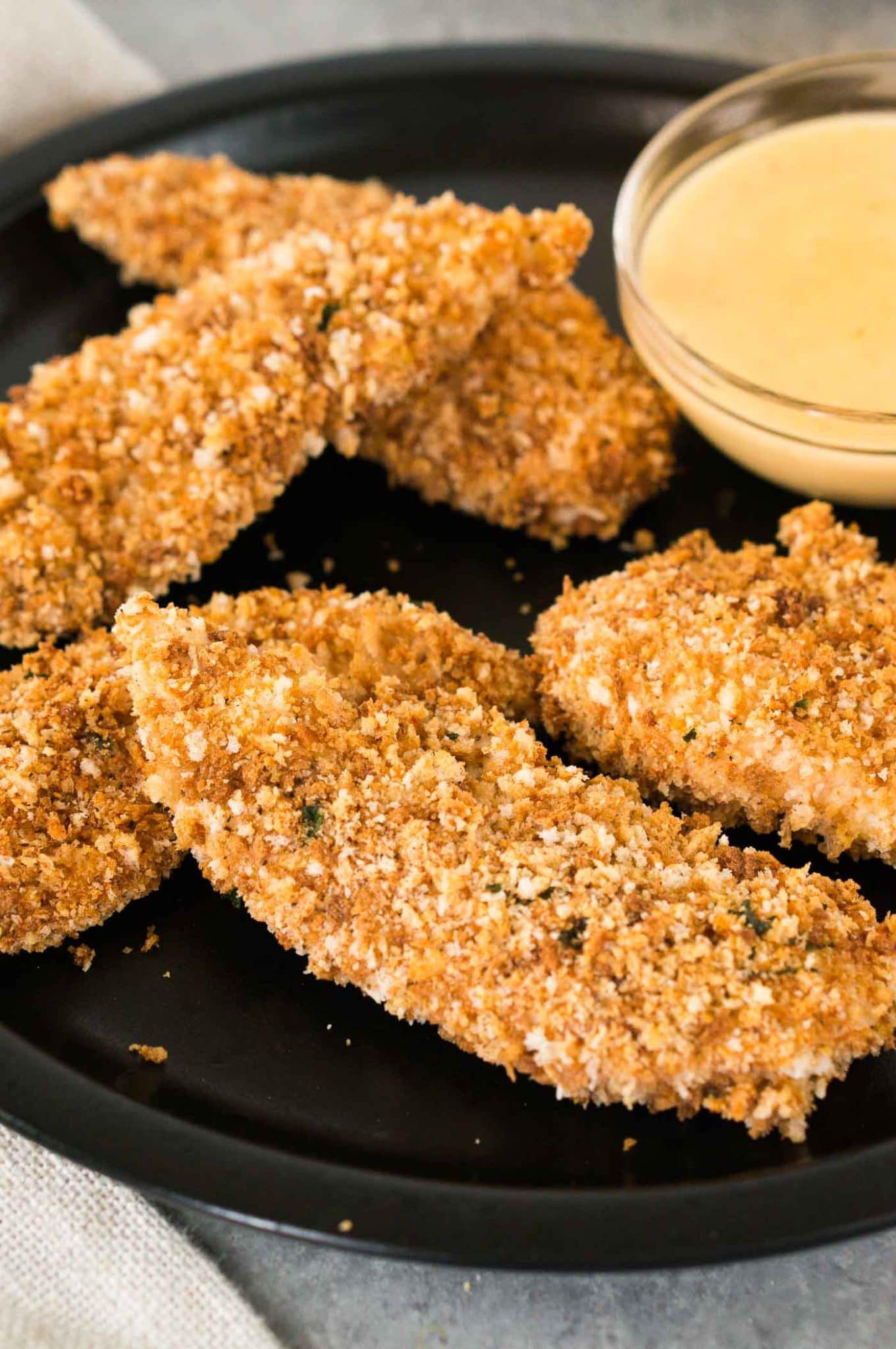 close up shot of crispy chicken tenders on a plate with dipping sauce