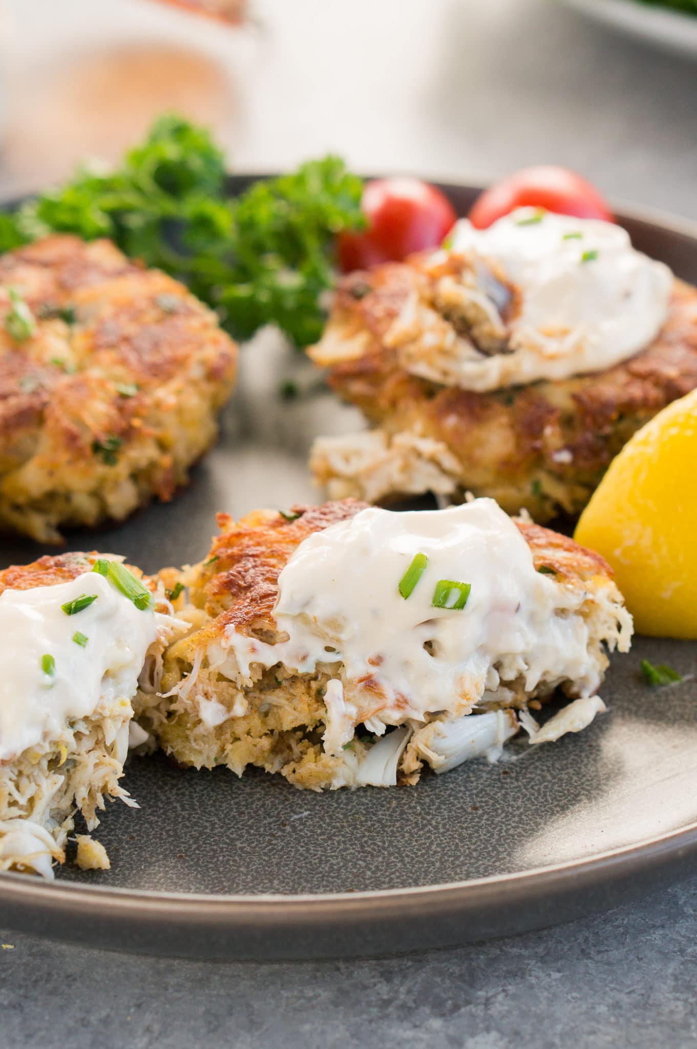 a bite of crab cakes with tartar sauce on a plate