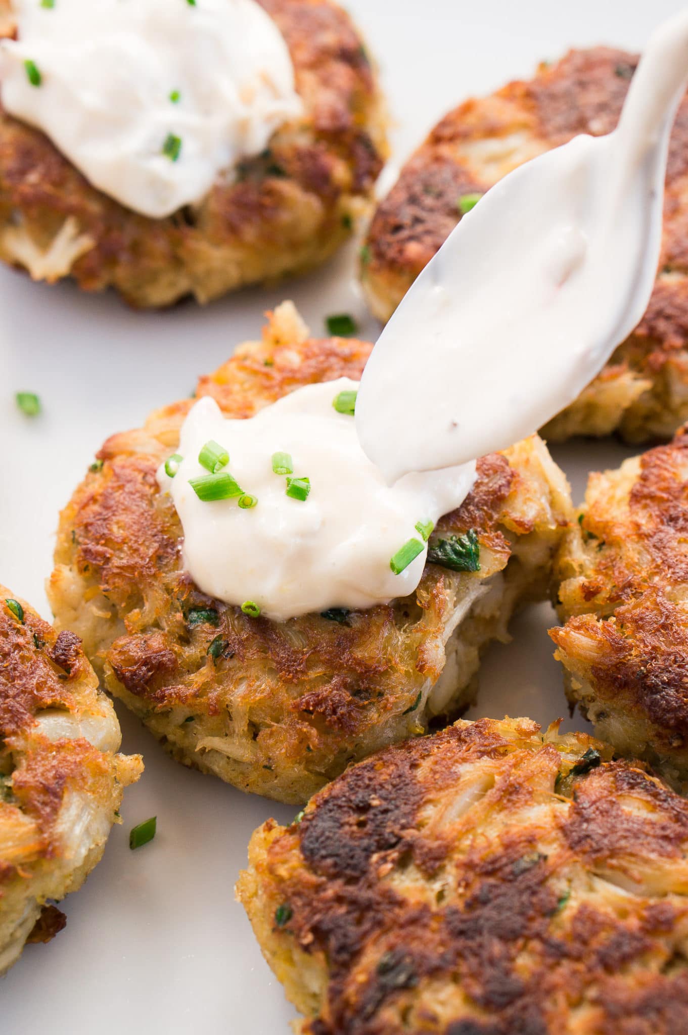 topping crab cakes with tartar sauce