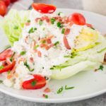 wedge salad with blue cheese dressing tomatoes and bacon on a plate