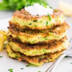 zucchini fritters with sour cream on top served on a plate