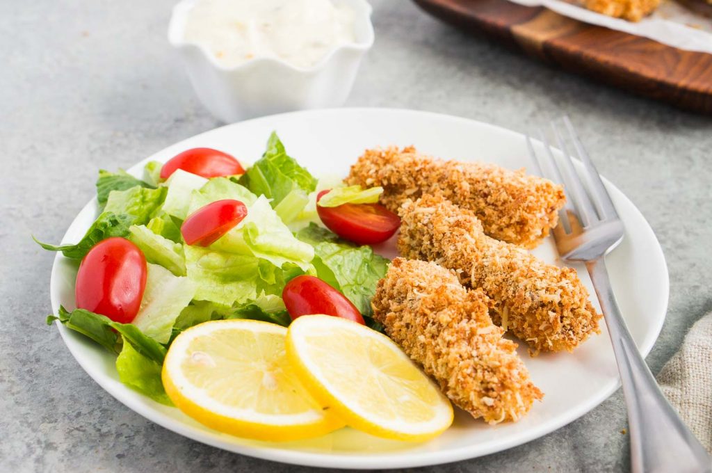 fish fingers served with salad and lemon slices on a plate