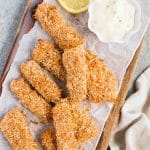 fish sticks on a wooden board with tartar sauce