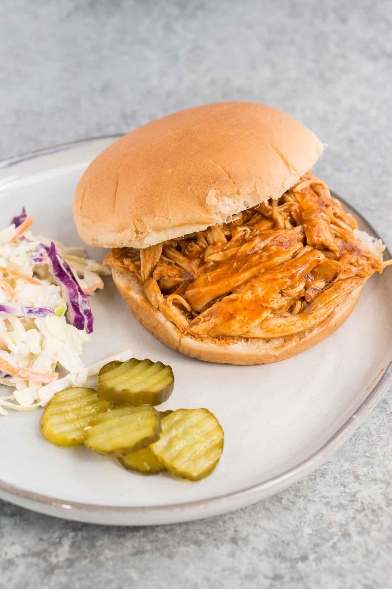 bbq chicken cooked in instant pot served on a plate with a bun