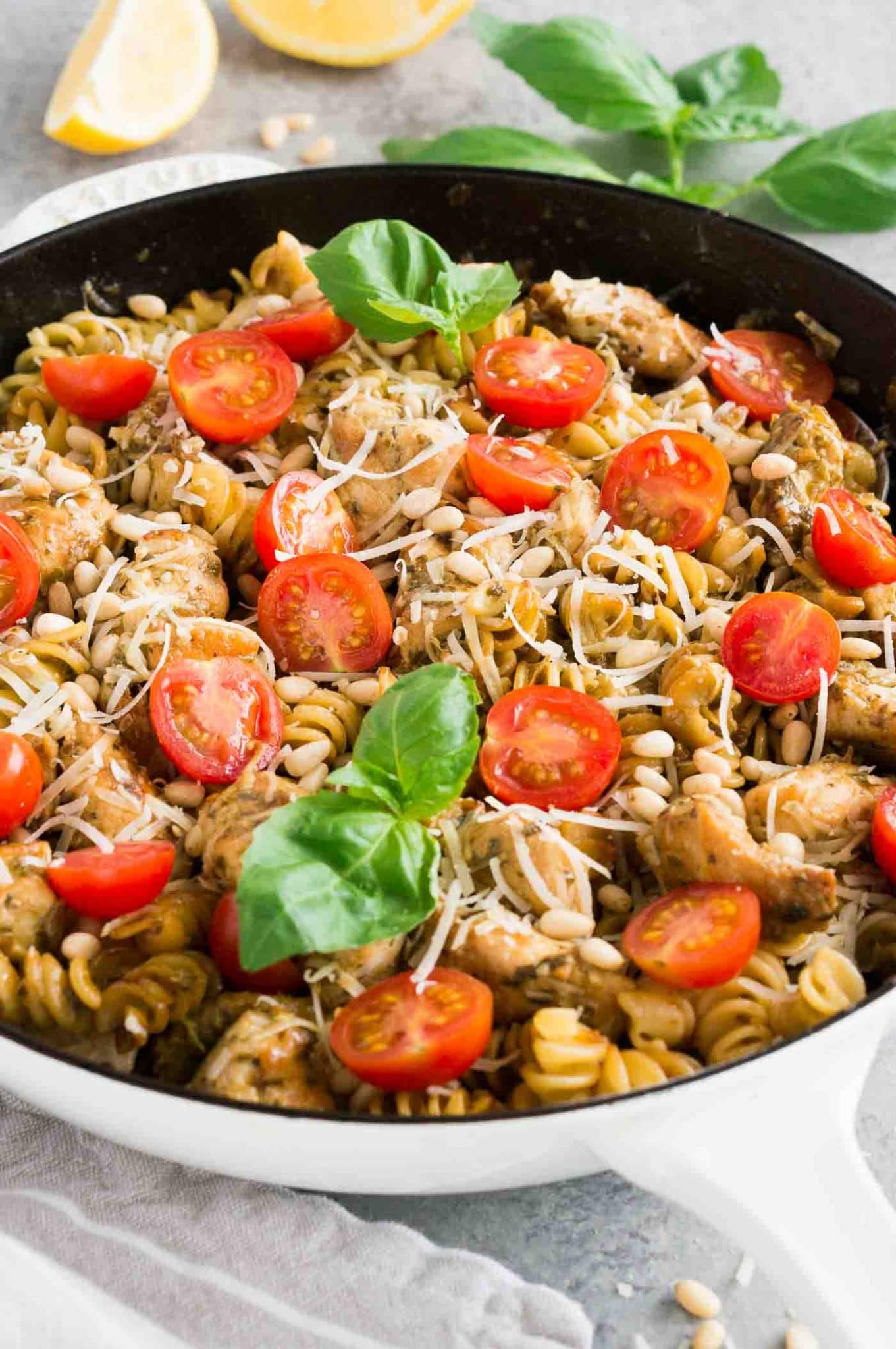 chicken pasta with pesto and tomatoes in a skillet