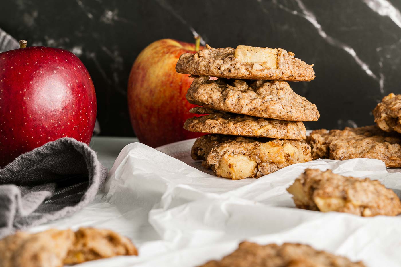 stacked oatmeal cookies and apples in background