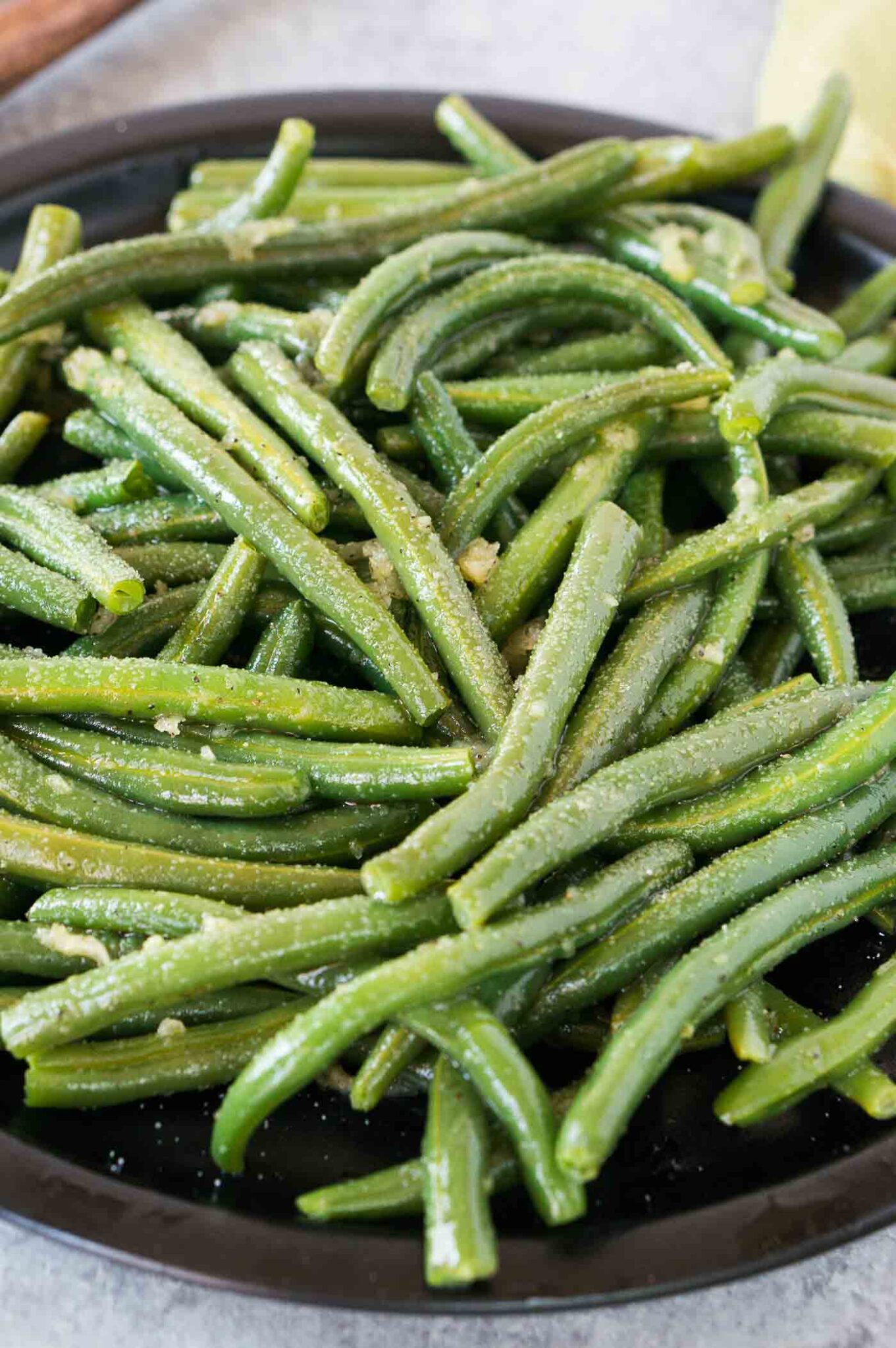 close up image of cooked green beans with seasonings served on a plate