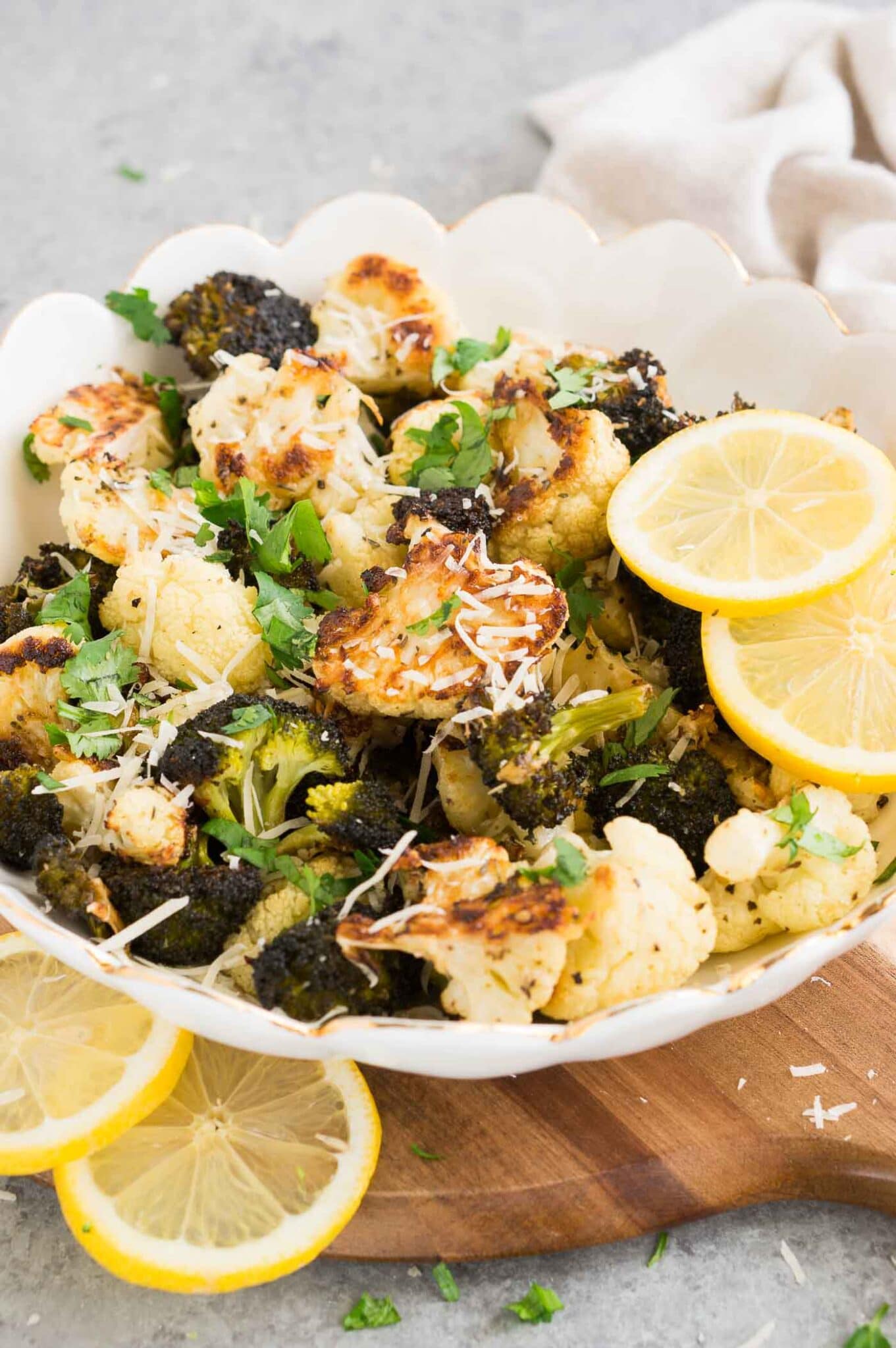 roasted cauliflower and broccoli florets in a bowl with parmesan cheese and lemon