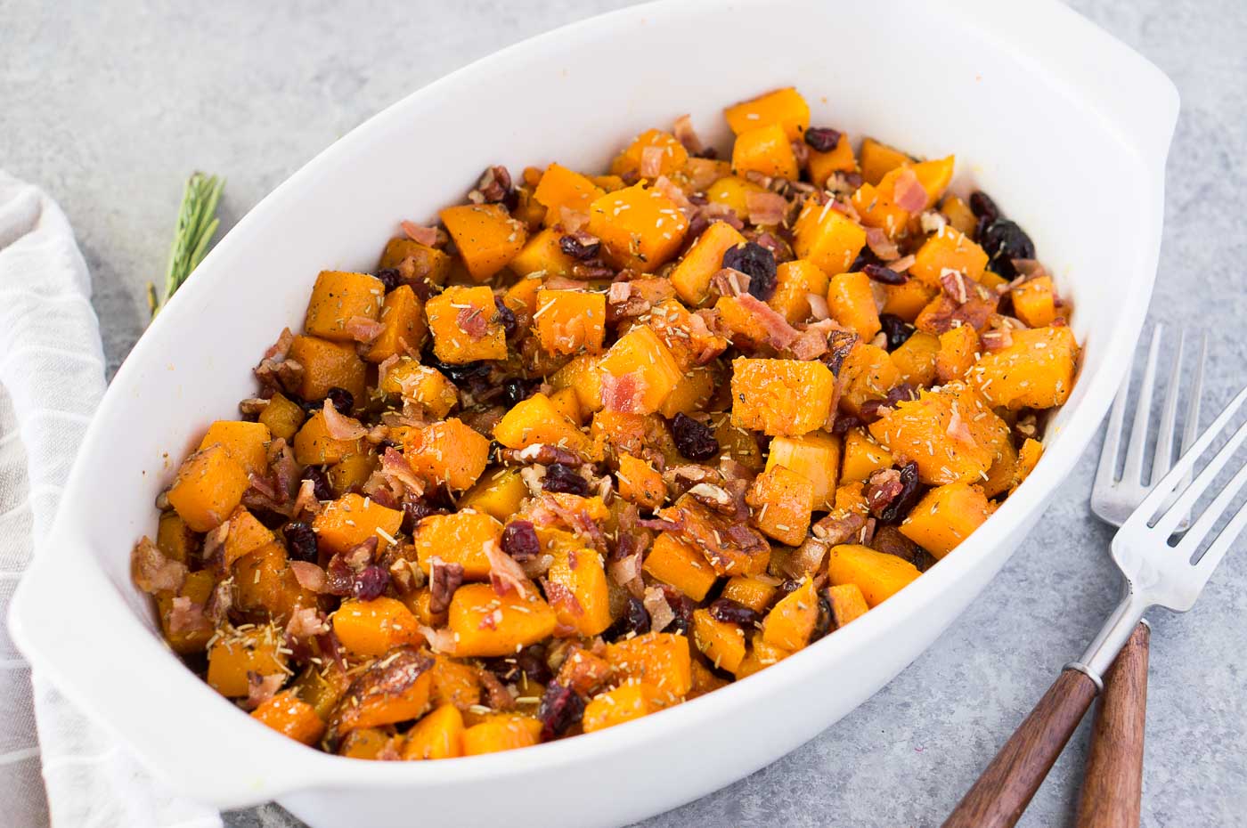close up of baked butternut squash with bacon and maple syrup in a dish
