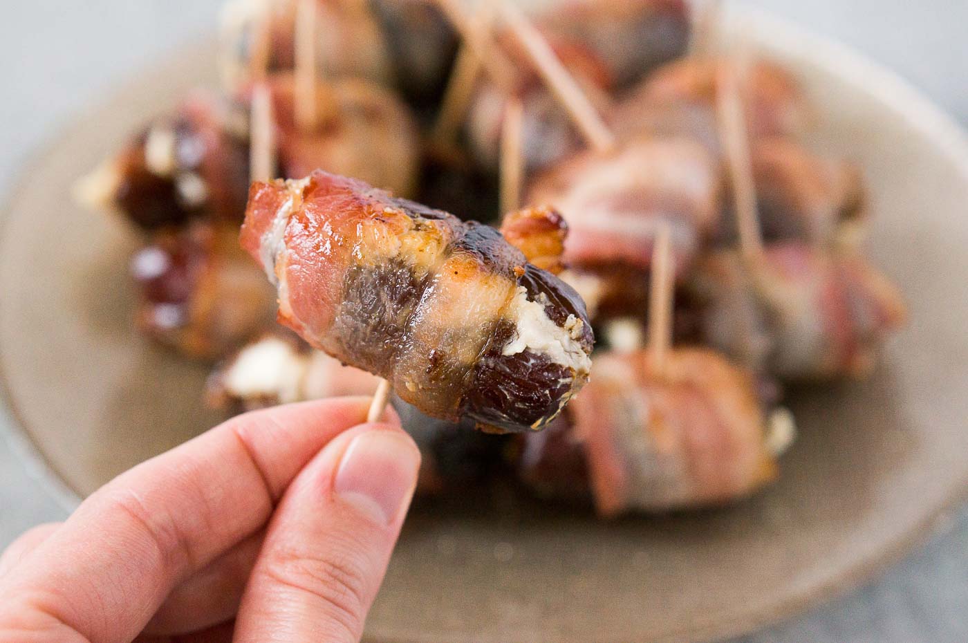 holding bacon wrapped dates with goat cheese