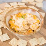 close up image of crab dip in a bowl with crackers