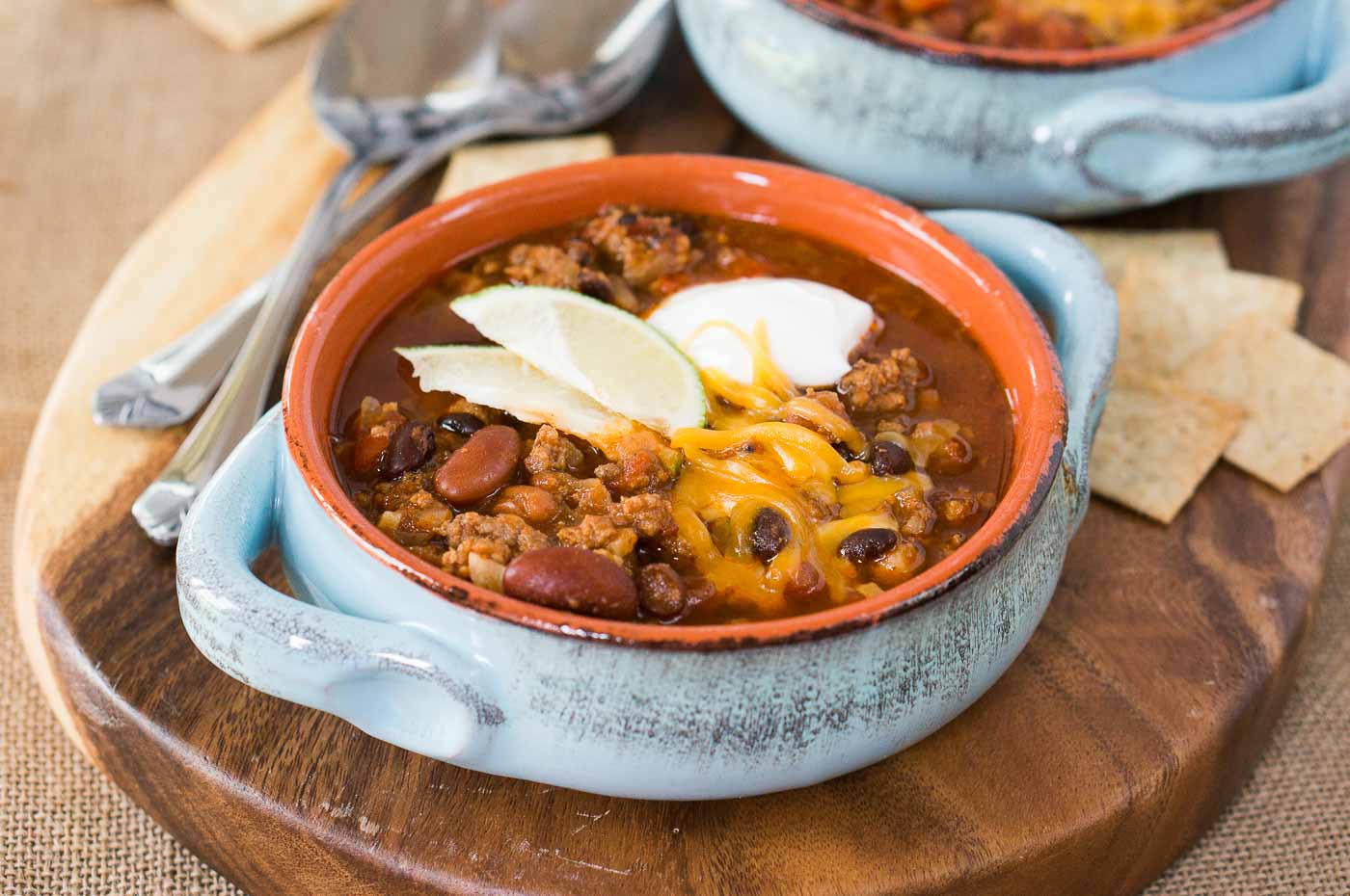 pressure cooker chili in a bowl with sour cream cheese and lime