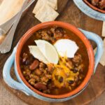 close up image of instant pot chili in a bowl with toppings