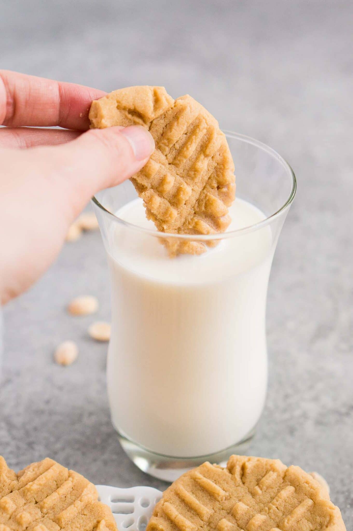 dipping peanut butter cookie in a glass of milk