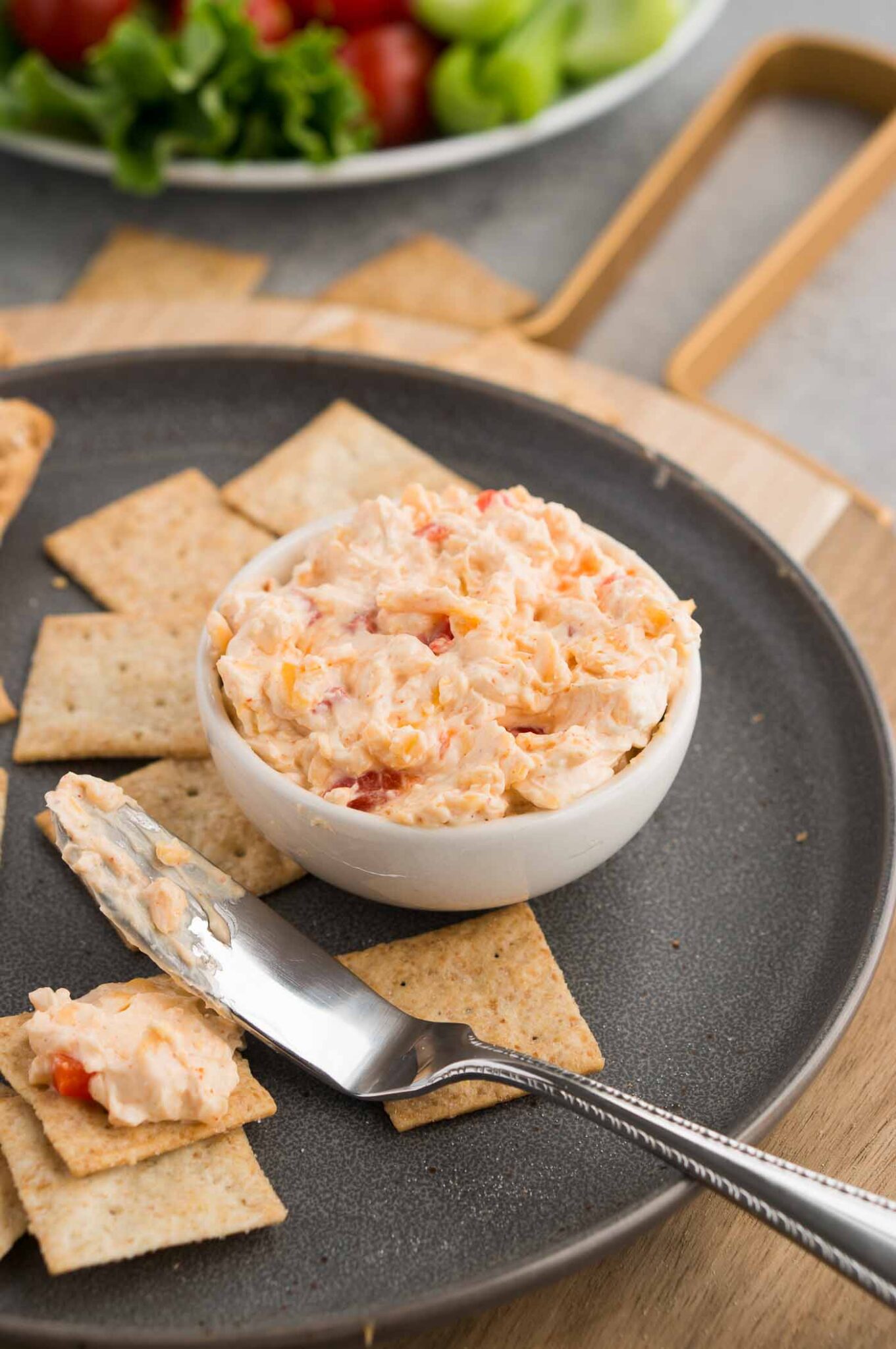 spreading pimento cheese on a cracker with a knife