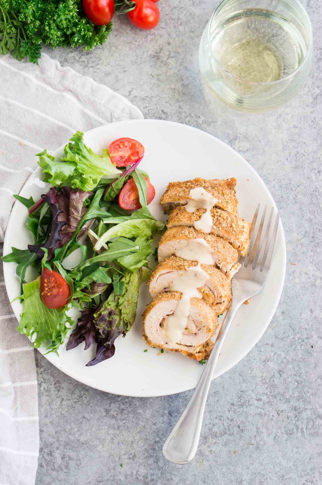 chicken cordon bleu with sauce and salad on a plate