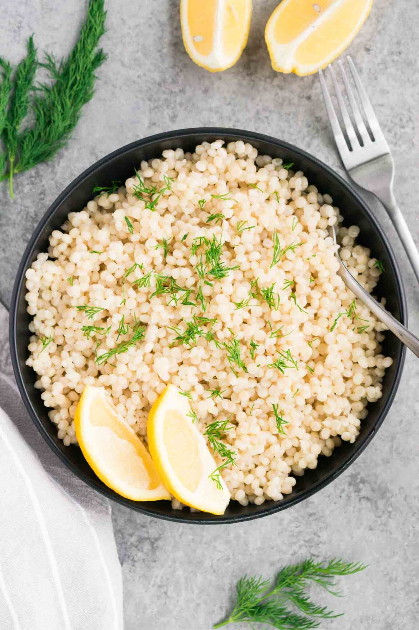 cooked couscous in a bowl with lemon slices