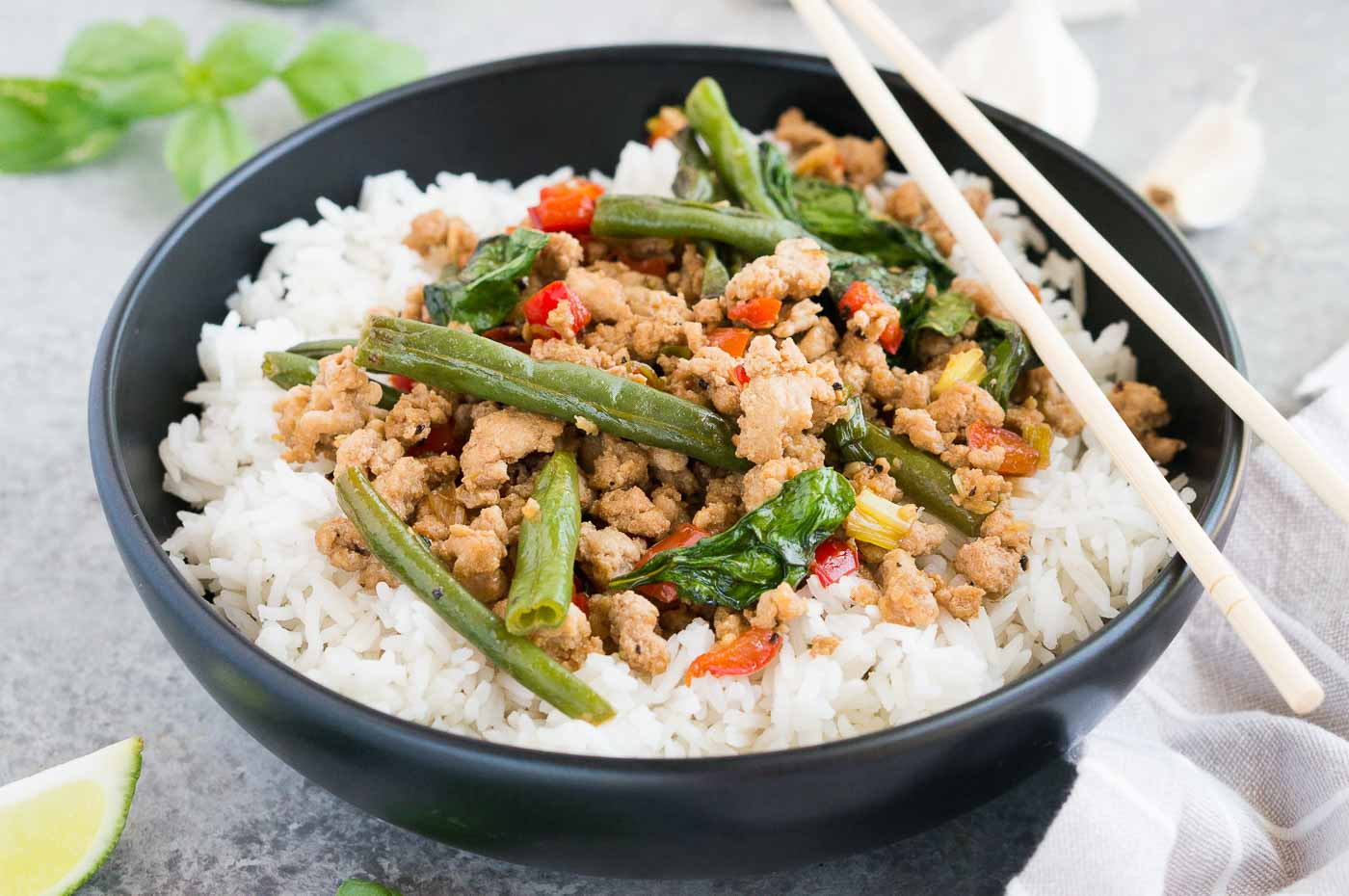 close up image of thai chicken basil recipe over rice in a bowl