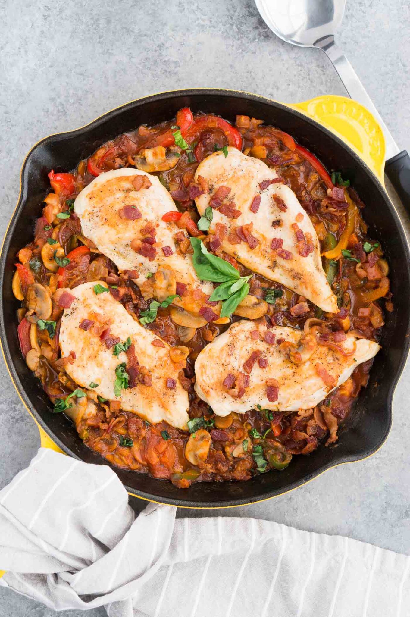 chicken and bacon added on top of cooked vegetables in a skillet