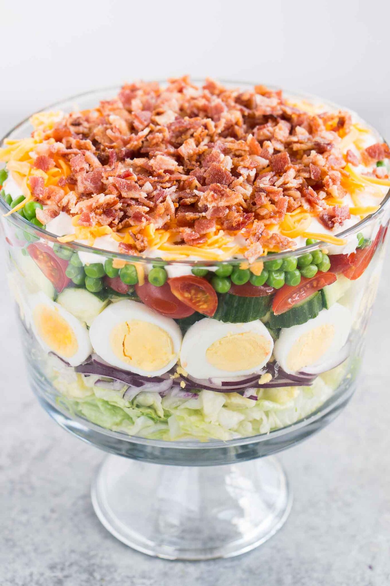 seven layer salad in a glass trifle dish